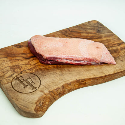 Raw meat on a wooden cutting board with a brand logo.