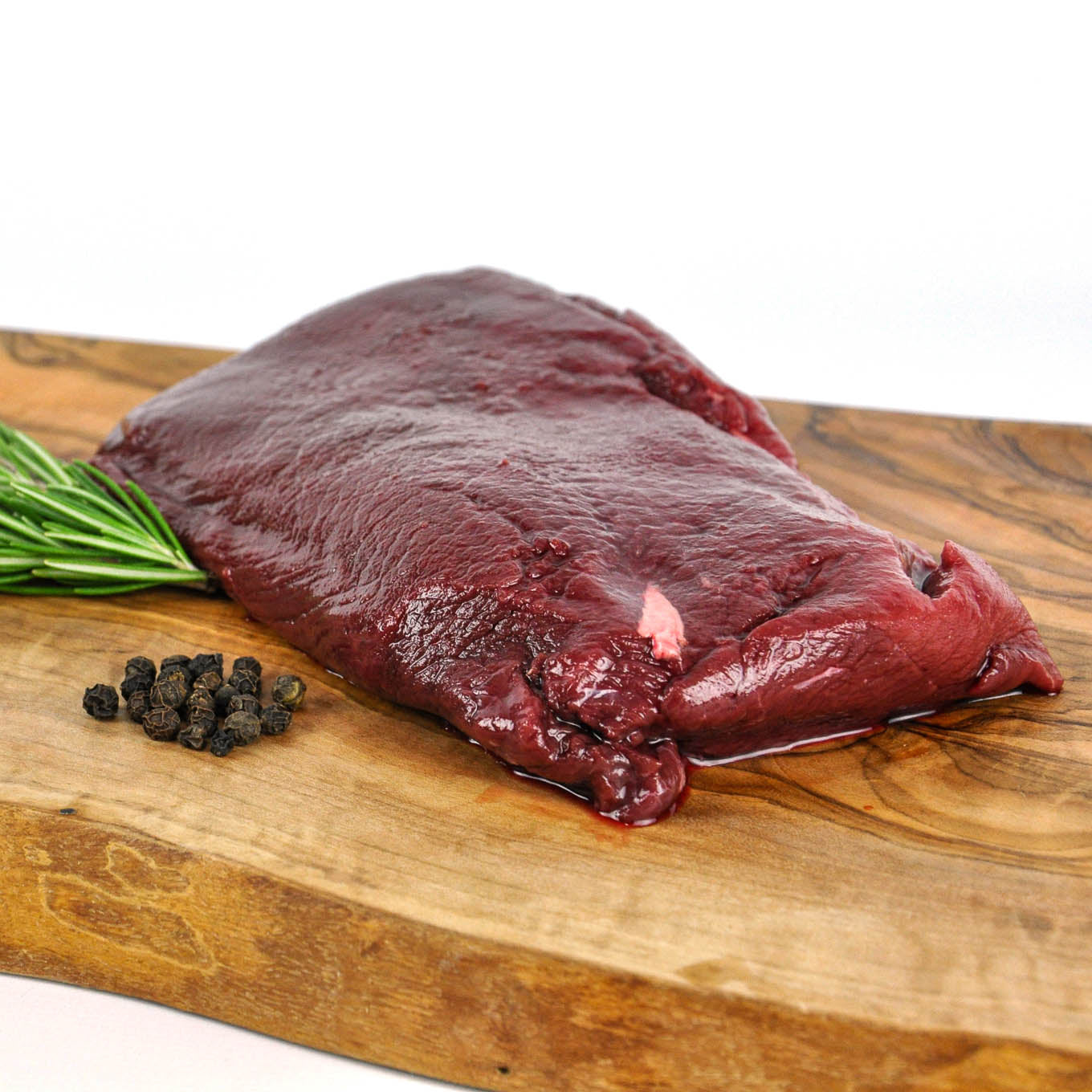 Raw meat on a wooden cutting board with peppercorns and rosemary.