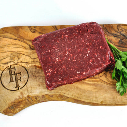 Raw ground beef on a wooden cutting board with a brand logo, on a white background