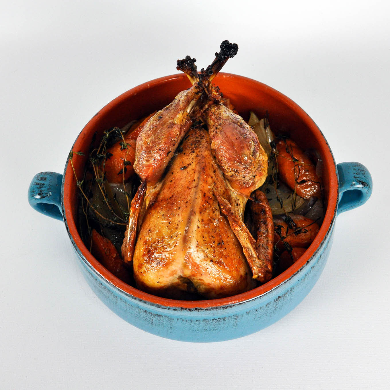 Roasted chicken in a blue ceramic dish on a white background
