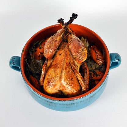 Roasted chicken in a blue ceramic dish on a white background