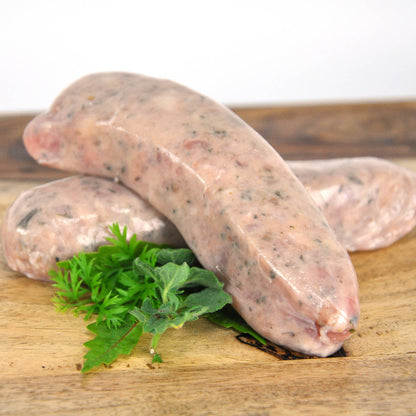 Raw sausages on a wooden board with herbs