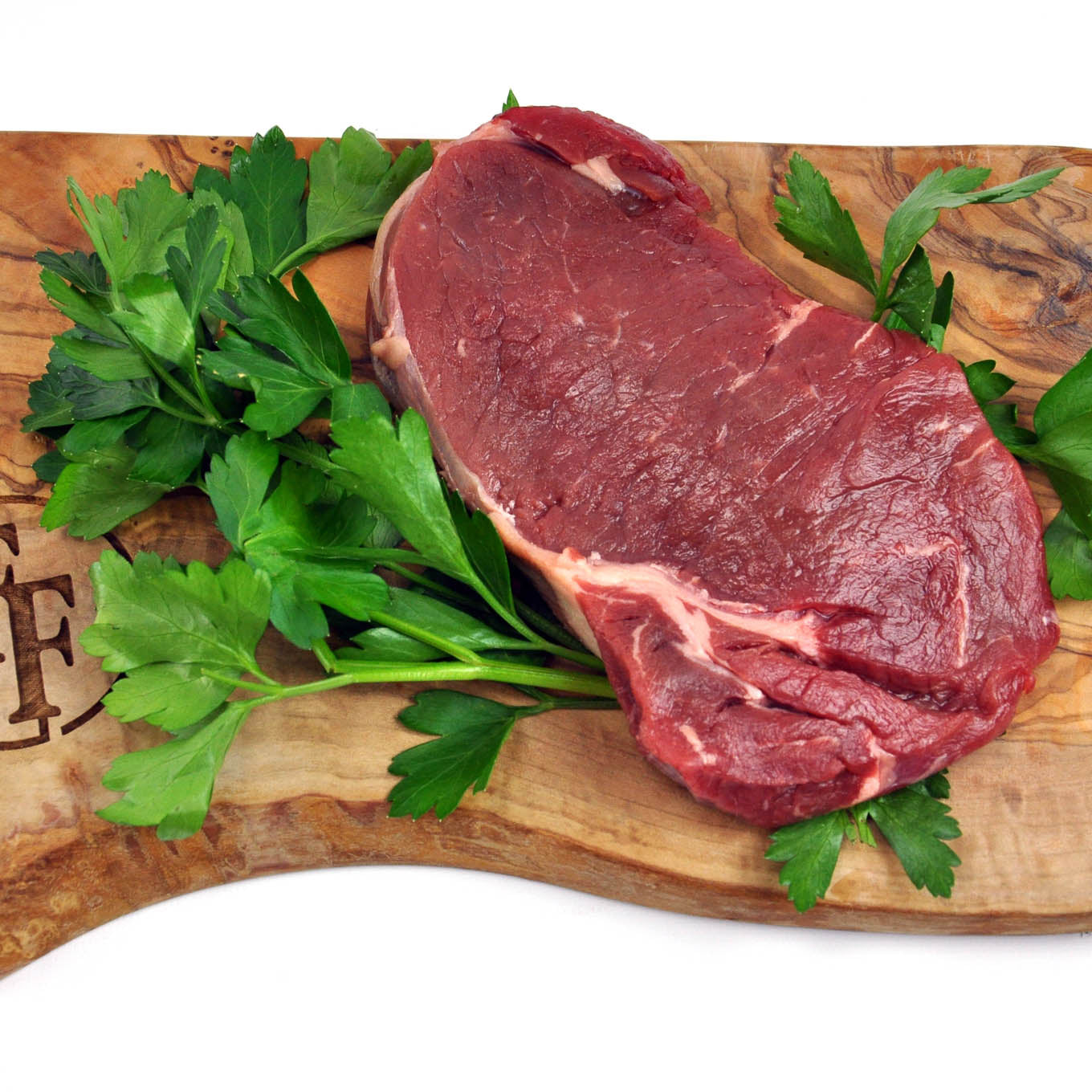 Raw steak on a wooden cutting board with parsley