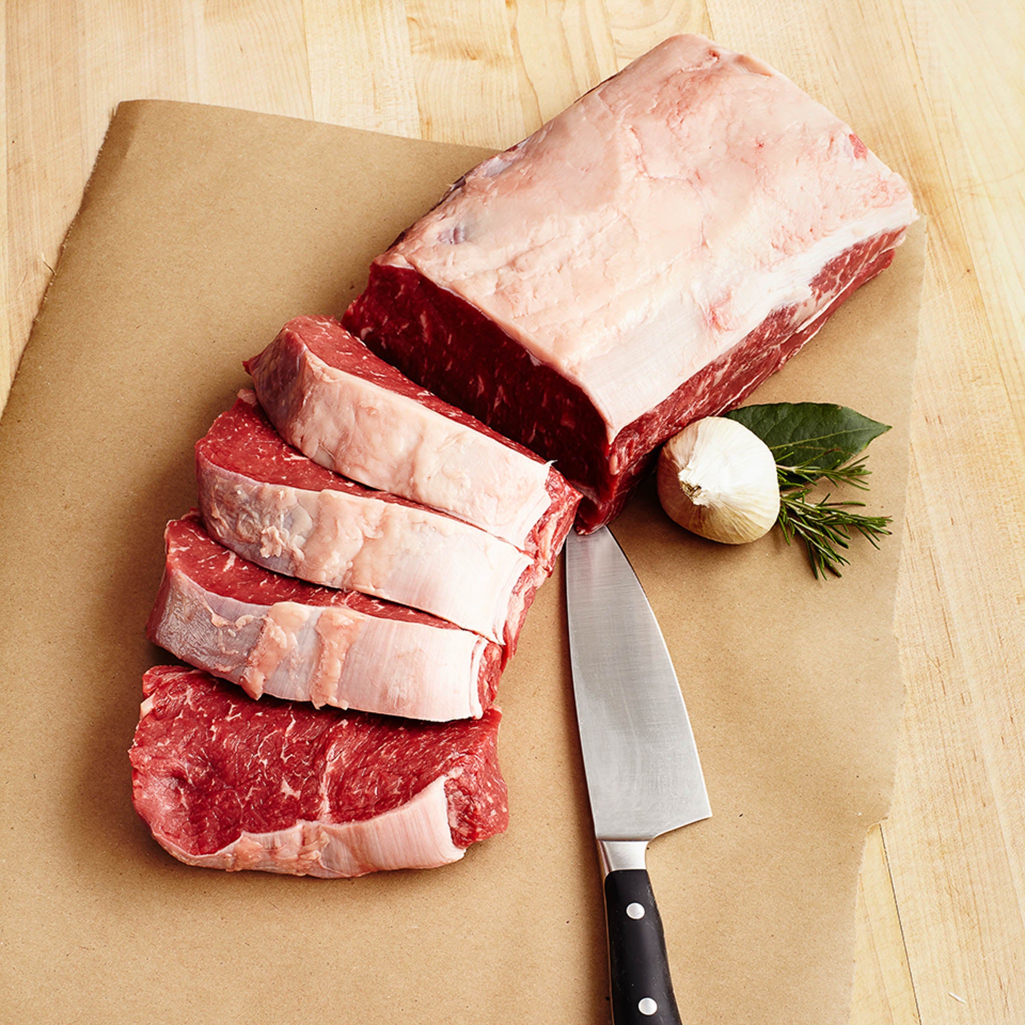 Raw ribeye steak with a knife on a wooden surface