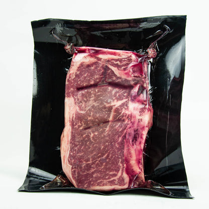 Vacuum-sealed package of raw steak on a white background