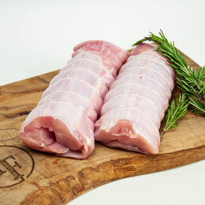 Raw pork belly slices on a wooden cutting board with rosemary