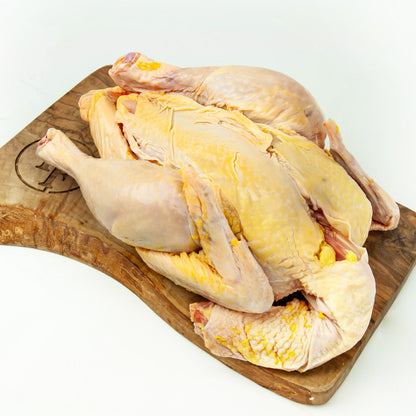 Raw chicken on a wooden cutting board with a white background
