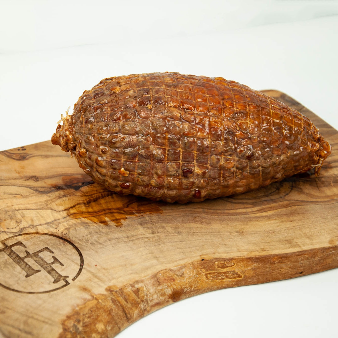 Cured meat on a wooden cutting board with a visible brand logo.