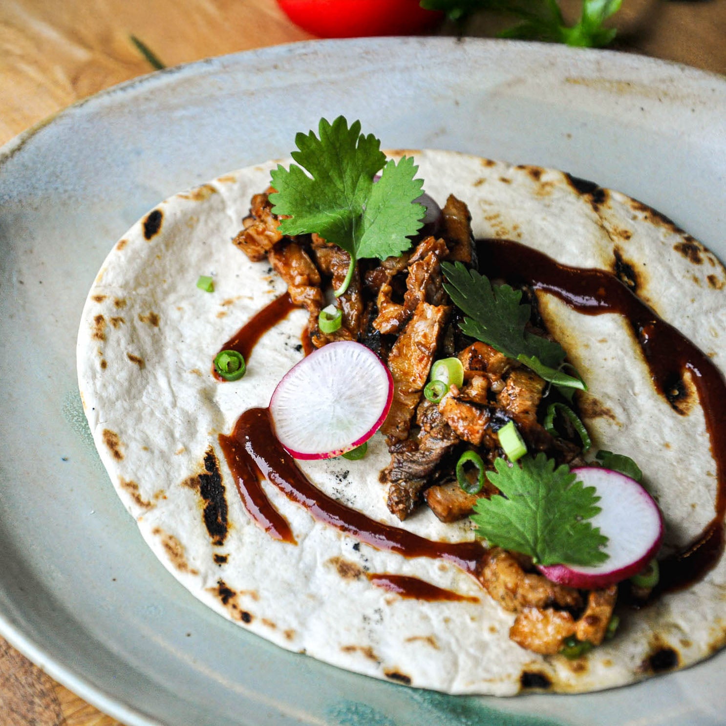 Tortilla with meat, radishes, and greens on a plate