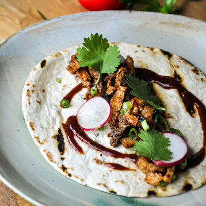 Tortilla with meat, radishes, and greens on a plate