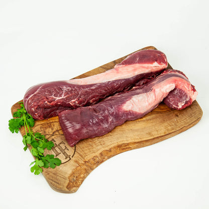 Raw meat on a wooden cutting board with herbs on a white background