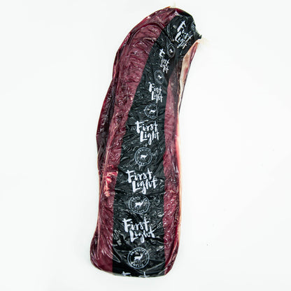 Raw meat slab with 'First Light' branding on a white background