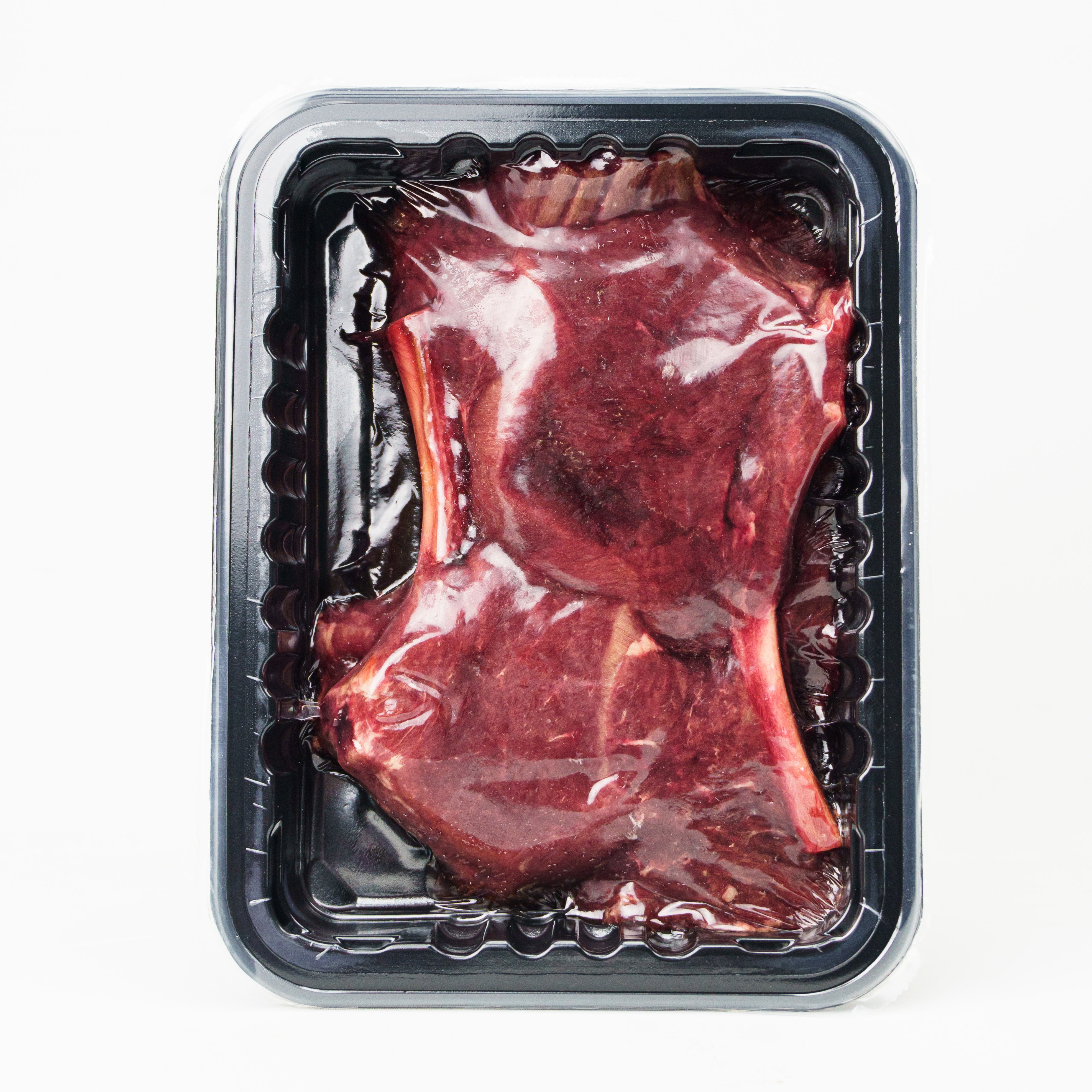 Raw meat in a clear plastic packaging on a white background