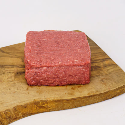 Block of ground meat on a wooden cutting board with a white background
