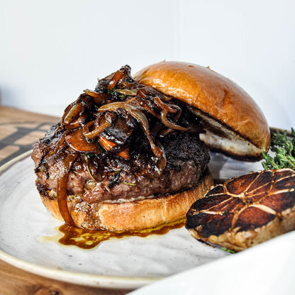 Hamburger with caramelized onions on a bun, served on a plate.