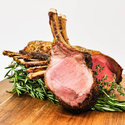 Roasted rack of lamb with herbs on a wooden cutting board