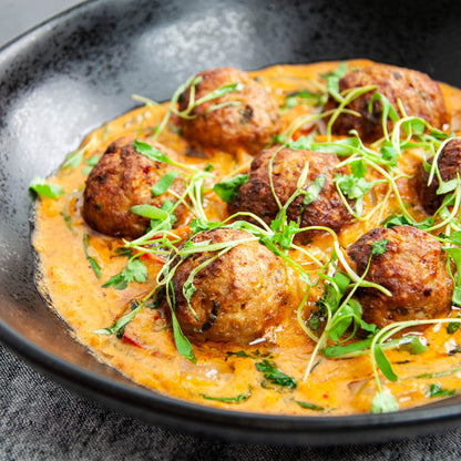 Dish with meatballs and creamy sauce on a dark plate