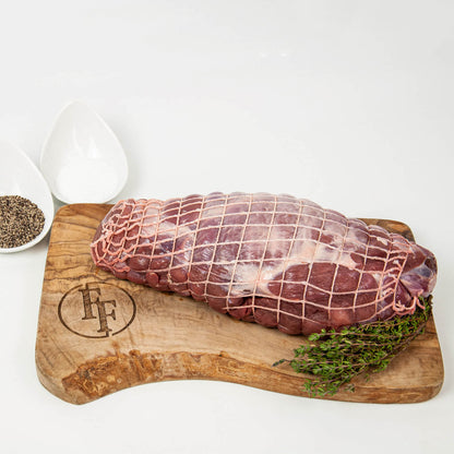 Raw meat on a wooden cutting board with herbs, branded 'FF' on a white background