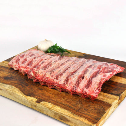 Raw ribs on a wooden cutting board with a white background