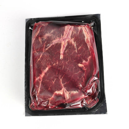 Vacuum-sealed package of raw beef on a white background