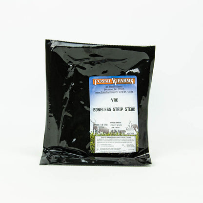 Black packaging of Fossil Farms yak boneless strip steak on a white background