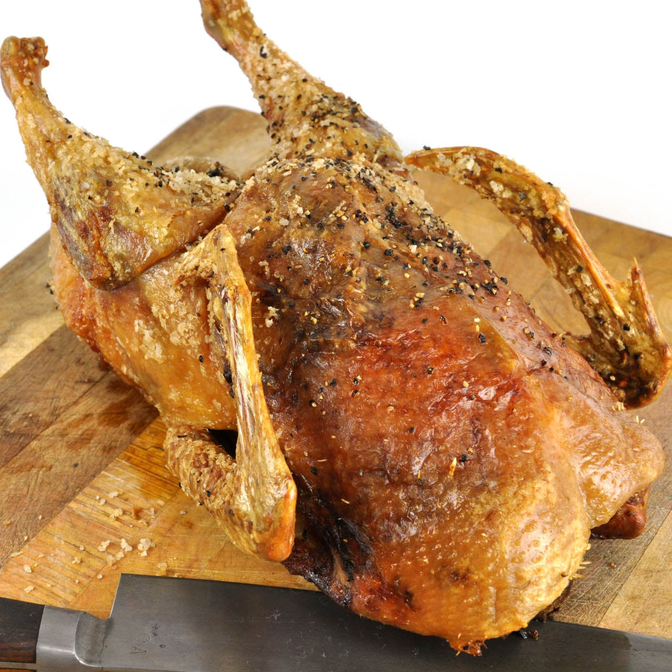 Roasted chicken on a wooden cutting board with a white background