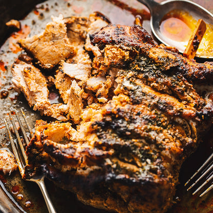 Sliced roasted meat on a plate with a spoon and fork
